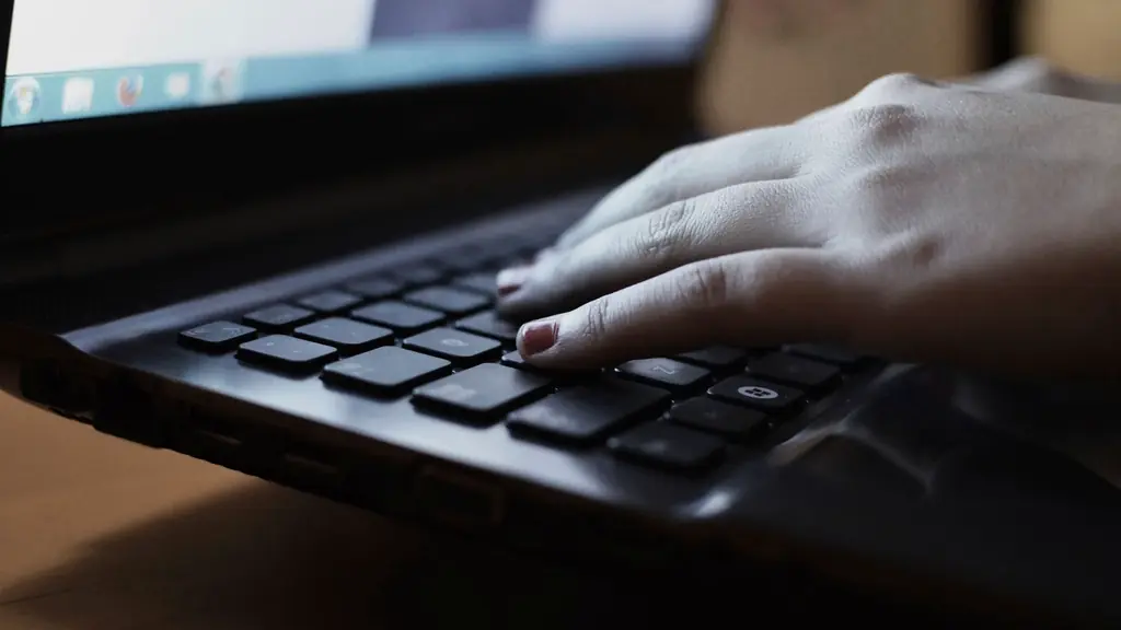 Hands typing on a laptop in low light
