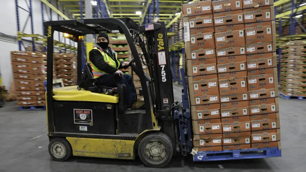 Forklift carrying a loaded pallet in a warehouse