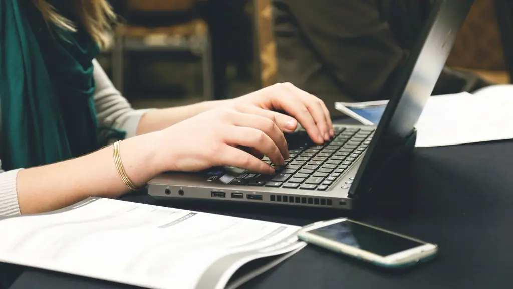 Hands typing on a laptop beside printed notes